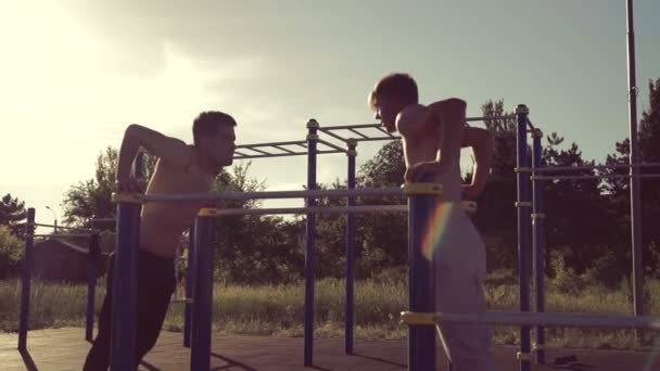 Dos hombres entrenando en barras transversales paralelas — Vídeos de Stock