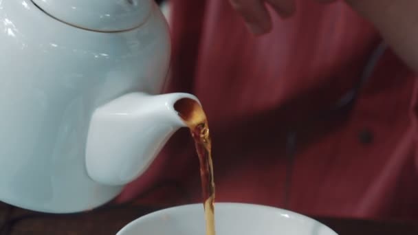 人用茶壶把茶倒入茶杯里 坐在咖啡馆里 — 图库视频影像