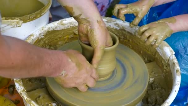 陶工の手が粘土からカップを形します 陶芸ろくろで陶器を作成するプロセス マスター陶芸家は 彼のスタジオで鍋をする生徒を教えています 手だけクローズ アップ — ストック動画