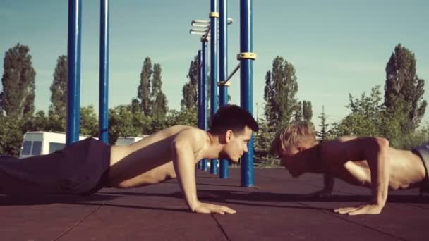 在户外锻炼与私人教练 两名男性运动员在公园里做板膝运动 作为锻炼套路的一部分 慢动作 — 图库视频影像