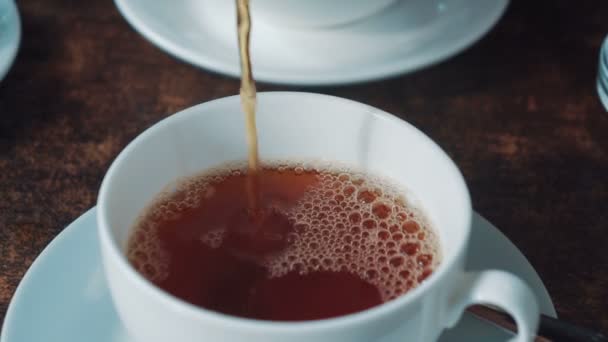 homme verse le thé dans une tasse avec une théière, assis dans un café. Gros plan .