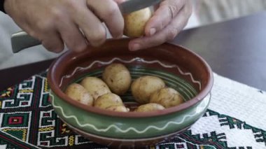 Ev mutfak patates soyarken oldu. A adam elinde bir bıçak ve patates soyma ve bir kase içinde temiz. Evde yemek pişirme.