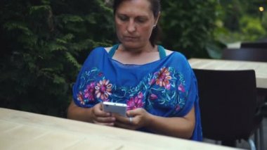 Açık kafede oturan Bayan portresi hir smartphone kullanır.