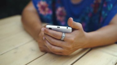 Açık kafede oturan Bayan portresi hir smartphone kullanır.