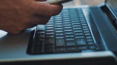 Adam parmak klavye dizüstü bilgisayar kaydediyor. Smartphone kullanır. Yakın çekim.