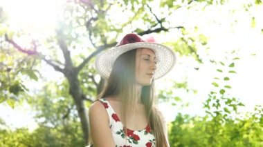 Işık beyaz elbise ve şapka yaz parkta duran güzel zarif bir kadın portresi.