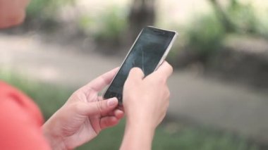 Smartphone dışında yeşil ağaçlar doğa geçmiş vasıl kullanan genç kadın. Genç kadın cep telefonuyla. Kadın mesaj sms telefonunda dışında Park.