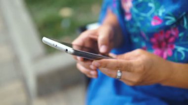 Smartphone açık havada ile inanılmaz bir kadın portresi. Güzel esmer parkta duran dokunmatik ekranlı cep telefonu kullanarak. Yakın çekim.