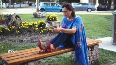 Smartphone açık havada ile inanılmaz bir kadın portresi. Güzel esmer parkta duran dokunmatik ekranlı cep telefonu kullanarak