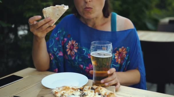 咖啡馆里的黑发女人正在吃美味的比萨饼和喝啤酒 — 图库视频影像