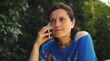 Bahçe ve cep telefonu üzerinde sohbet kafede oturan güzel kadın