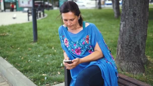 在户外智能手机的惊人的女人的肖像 漂亮的黑发使用她的手机与触摸屏站在公园 — 图库视频影像