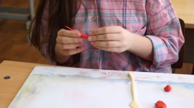 renkli modelleme hamuru odasında yapılmış küçük kız masa başında oturan farklı rakamları sculpts.