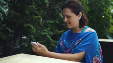 Açık kafede oturan Bayan portresi hir smartphone kullanır.