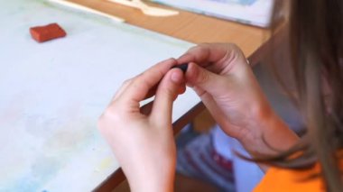 renkli modelleme hamuru odasında yapılmış küçük kız masa başında oturan farklı rakamları sculpts.