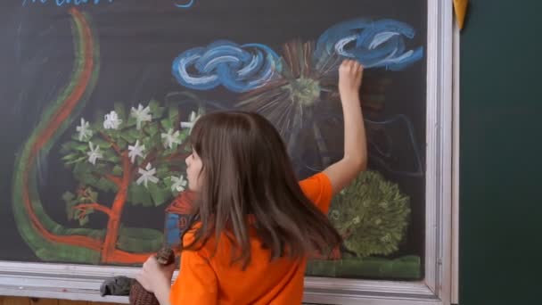 小さな女の子が黒板にチョークを描画します — ストック動画