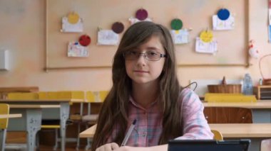 Sınıfta oturmuş kamera için gözlük - lise öğrencisi genç kız gülümsüyor