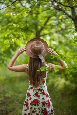 Işık beyaz elbise ve şapka yaz parkta duran güzel zarif bir kadın portresi.