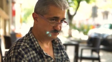 Kameraya bakarak ve gülümseyen Gözlüklü olgun, çekici bir adam portresi.