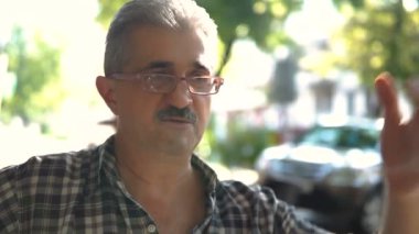 Kameraya bakarak ve gülümseyen Gözlüklü olgun, çekici bir adam portresi.