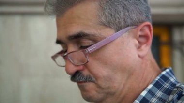 Kameraya bakarak ve gülümseyen Gözlüklü olgun, çekici bir adam portresi.