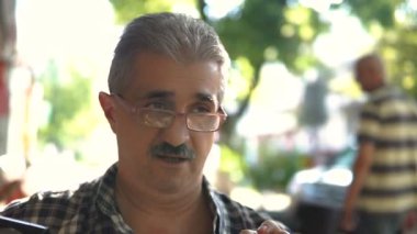 Kameraya bakarak ve gülümseyen Gözlüklü olgun, çekici bir adam portresi.