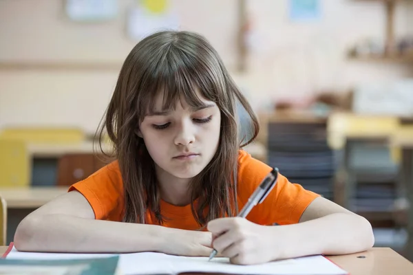 Kleines Mädchen Schreibt Etwas Ins Textbuch Und Sitzt Tisch — Stockfoto