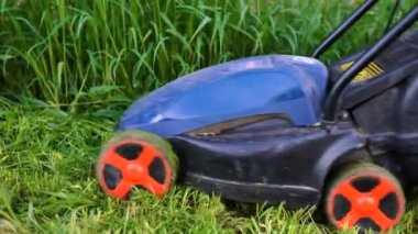 Çim biçme makinesiyle çim biçen bir işçi.