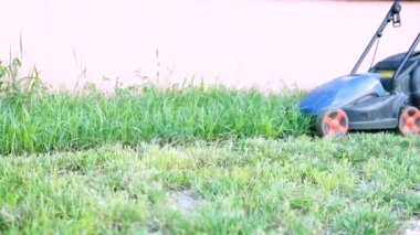 Çim biçme makinesiyle çim biçen bir işçi.