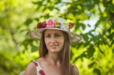 Işık beyaz elbise ve şapka yaz parkta duran güzel zarif bir kadın portresi.