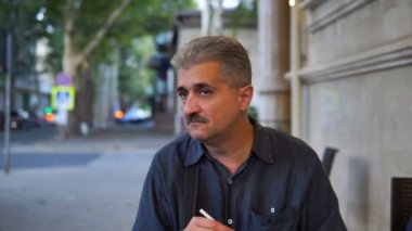 Yetişkin adam kamera ve sigara sigarette kafede oturmuş.