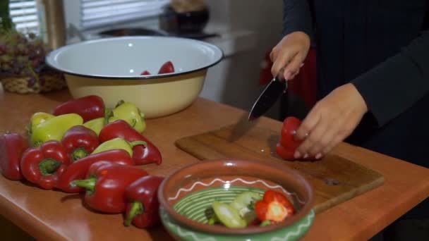 年轻妇女切片甜红色和黄色胡椒在一个木制的切割板 替身拍摄 — 图库视频影像