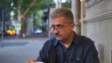 Yetişkin adam kamera ve sigara sigarette kafede oturmuş.