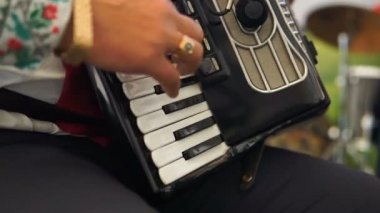 Yetişkin bir adam bir akordeon bir ulusal kostüm çalış. İskambil müzik dörtlüsü. Müzisyenler konserde gerçekleştirme.