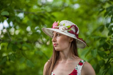 Işık beyaz elbise ve şapka yaz parkta duran güzel zarif bir kadın portresi.