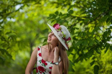 Işık beyaz elbise ve şapka yaz parkta duran güzel zarif bir kadın portresi.