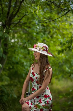 Işık beyaz elbise ve şapka yaz parkta duran güzel zarif bir kadın portresi.