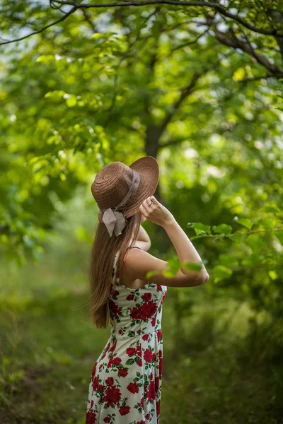 一个美丽优雅的女人在白色的礼服和帽子站在夏季公园的肖像 — 图库照片