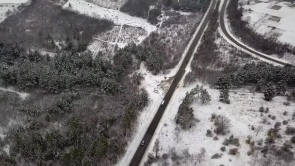 牧歌的な冬の風景の中に道路の空中ドローンビュー 鳥の目線で自然の中を走る通り — ストック動画