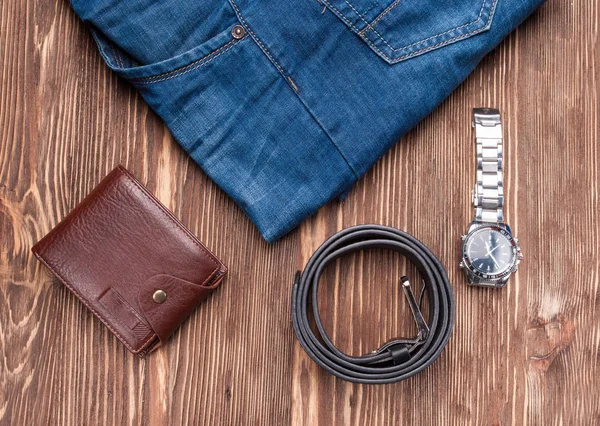 Jeans, belt and wallet, accessories for man on brown wooden table