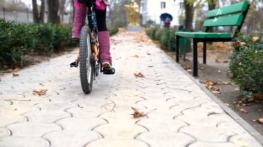 Bir beyaz çocuk sürmek Sonbahar Park yol bisiklet. Küçük kız parkta siyah turuncu döngüsü sürme. Evlat gider spor bisiklet.