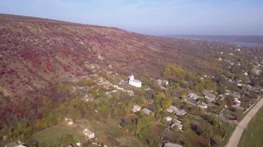 Kamera, Moldova Cumhuriyeti 'ndeki Ortodoks Kilisesi ve küçük bir köy üzerinde uçuyor..