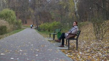 Mutlu kadın parkta bankta rahatlatıcı. Sonbahar.