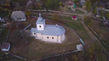 Kamera, Moldova Cumhuriyeti 'ndeki Ortodoks Kilisesi ve küçük bir köy üzerinde uçuyor..