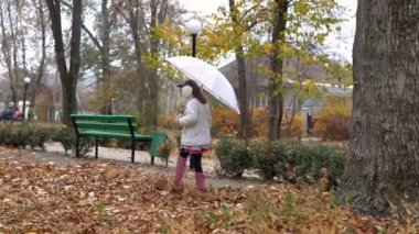 kadın çocuk sonbahar ellerinde sarı yaprakları ile bir parkta bir şemsiye altında yürüyor