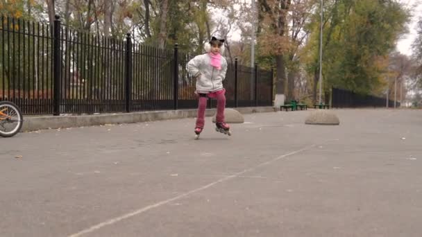 女孩骑在秋天公园在滑旱冰 体育和娱乐 — 图库视频影像