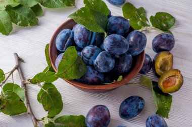 Ahşap masa üzerinde kase taze erik. Doğal gıda.