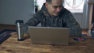 Genç erkekler evde bir dizüstü bilgisayarda çalışıyor. Uzak istihdam, freelancing