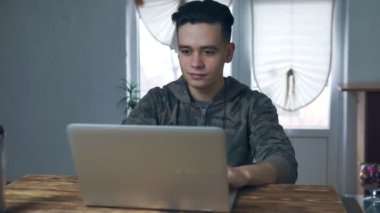 Evdeki dizüstü bilgisayarda çalışan genç adam. Heyecanlı ve mutlu iyi haber aldı. Uzaktan serbest çalışma. Başarı kavramı.