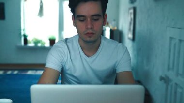 Adam evde bir dizüstü bilgisayarda çalışıyor.